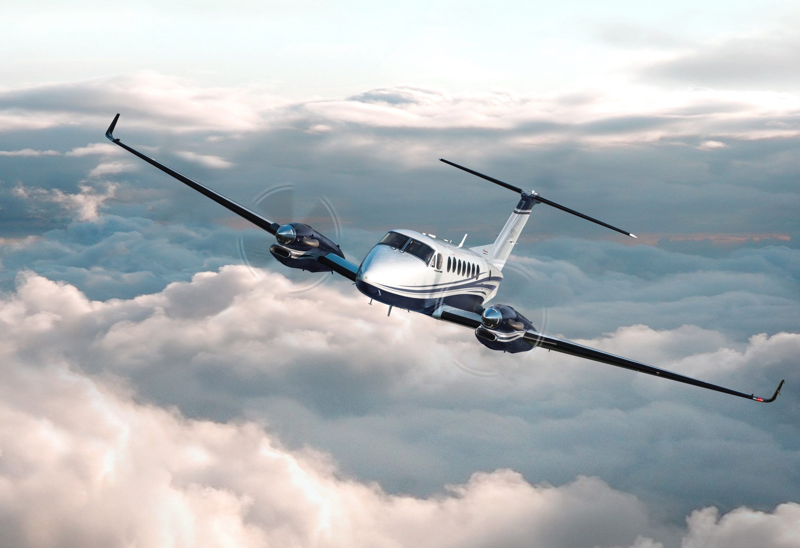A King Air banking over the clouds at altitude